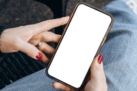 Close-up of a person with red nail polish holding a smartphone with a blank black screen. They are seated outdoors on a woven chair, wearing blue jeans and a black sweater.